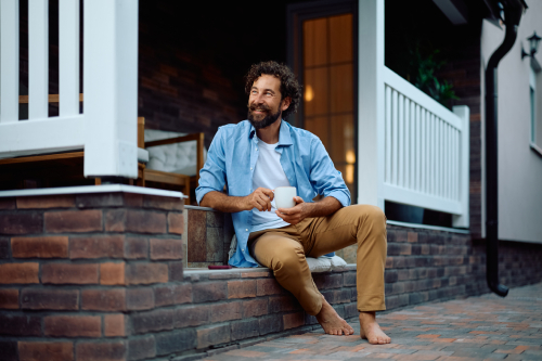 Man sitting on steps drinking coffee.